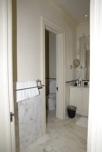 Badezimmer: EFTA00000239 - Bathroom with white marble flooring walls and cabinetry featuring a towel r
