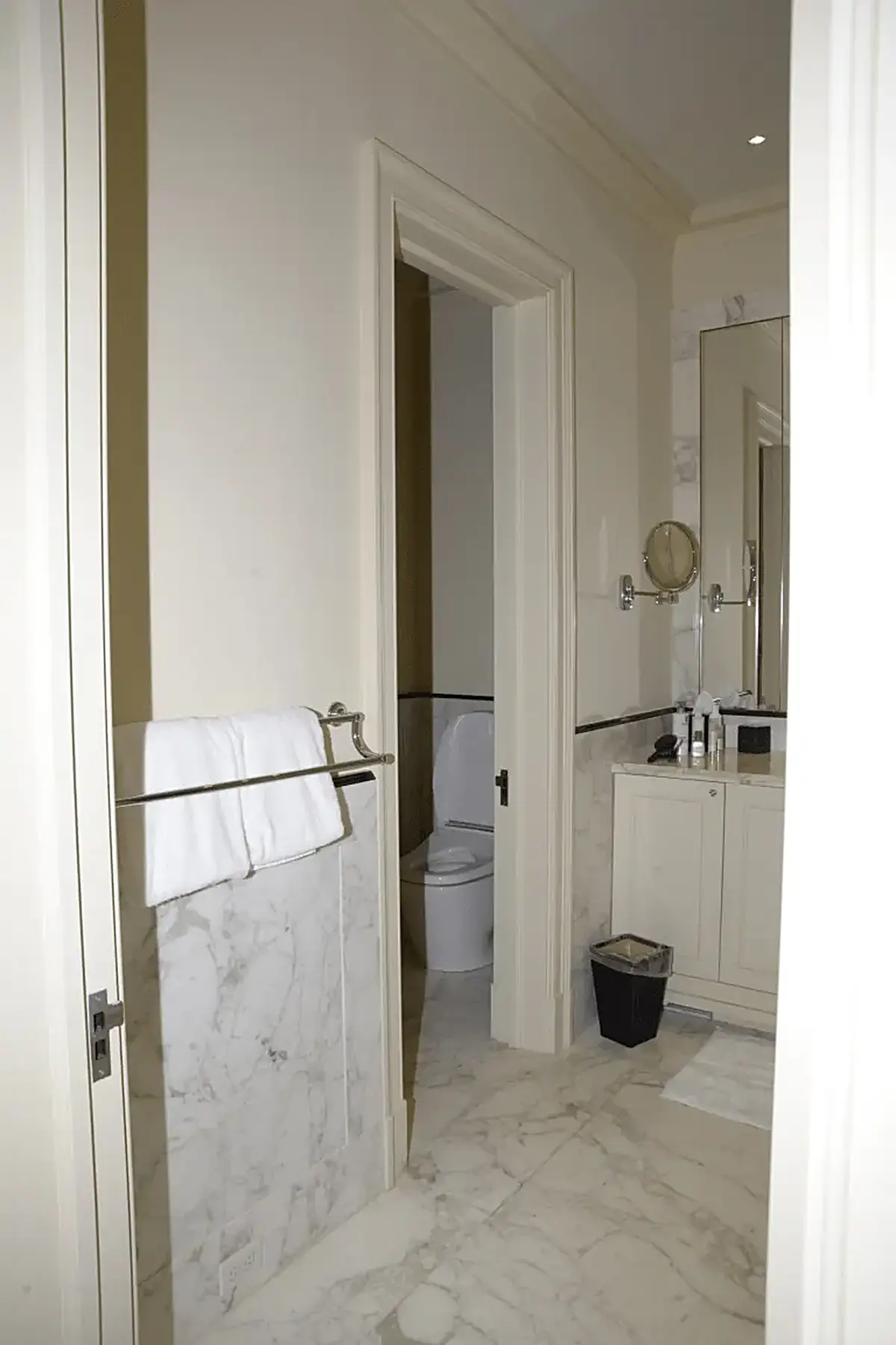 Badezimmer: EFTA00000239 - Bathroom with white marble flooring walls and cabinetry featuring a towel r