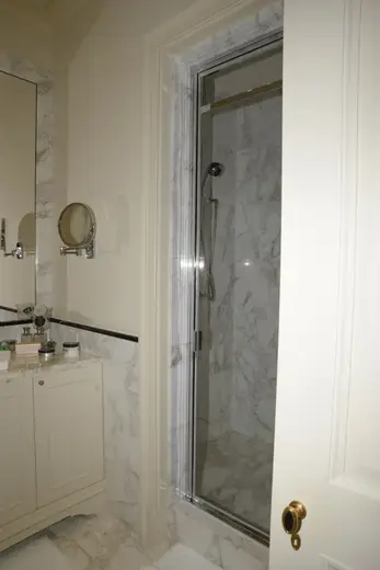 Badezimmer: EFTA00000240 - Bathroom featuring marble walls a glass shower enclosure a vanity with toil
