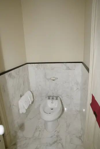 Badezimmer: EFTA00000241 - White bidet in a marble-walled bathroom with folded towels on the wall and 