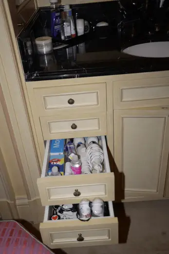 Badezimmer: EFTA00000505 - Bathroom vanity with open drawers revealing toiletries toothbrushes and per