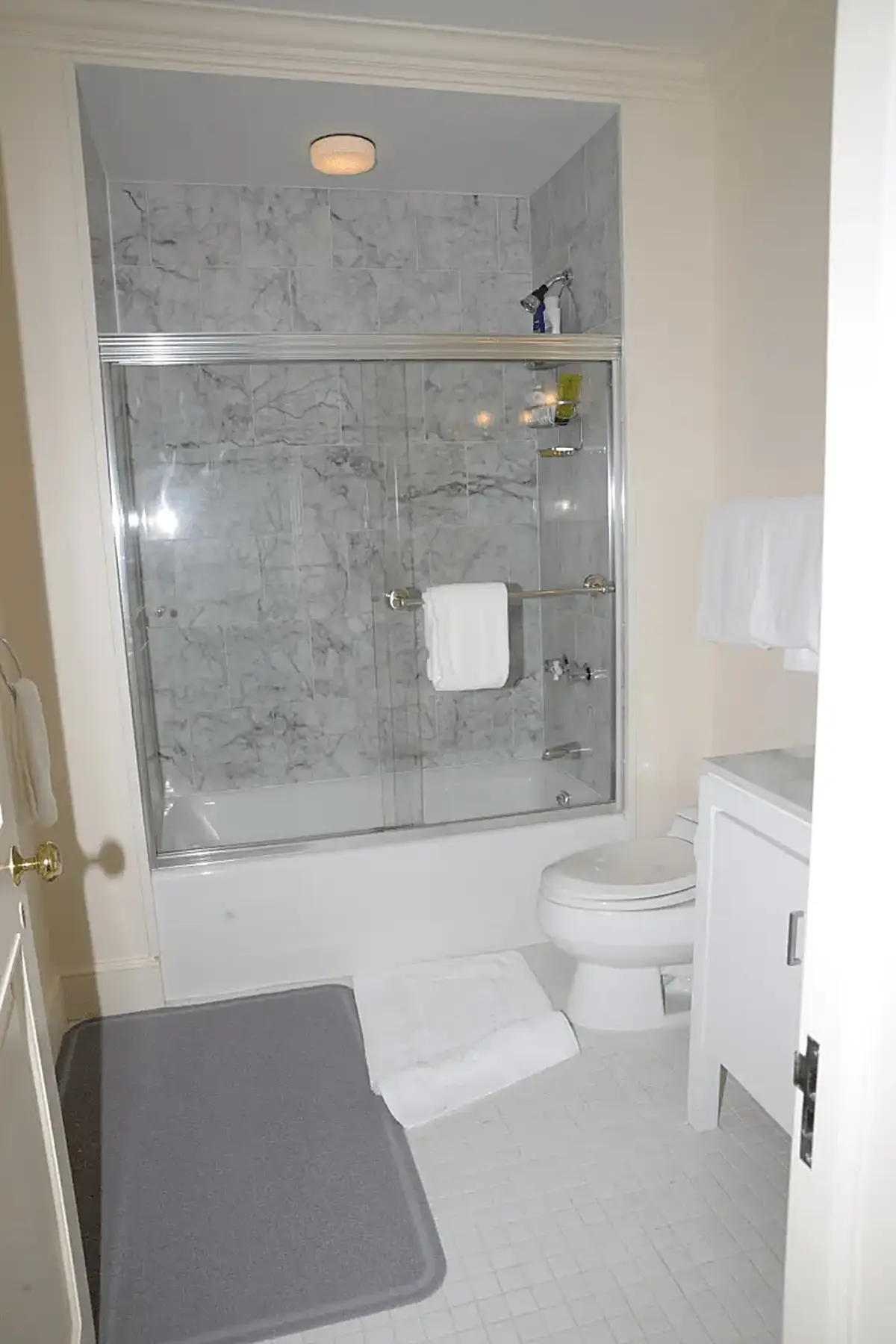 Ванная: EFTA00000562 - Clean bathroom featuring a marble-tiled shower white toilet and tiled floor