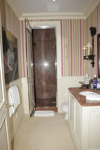 Badezimmer: EFTA00000596 - Bathroom with striped walls a marble shower white cabinets and a patterned 