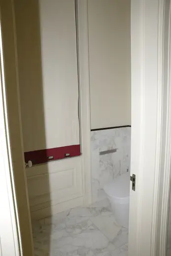 Badezimmer: EFTA00000604 - Bathroom with white marble flooring a modern toilet and a red trim on the w