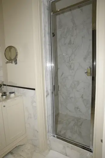 Badezimmer: EFTA00000605 - Luxurious bathroom featuring marble walls a glass shower door and a vanity 