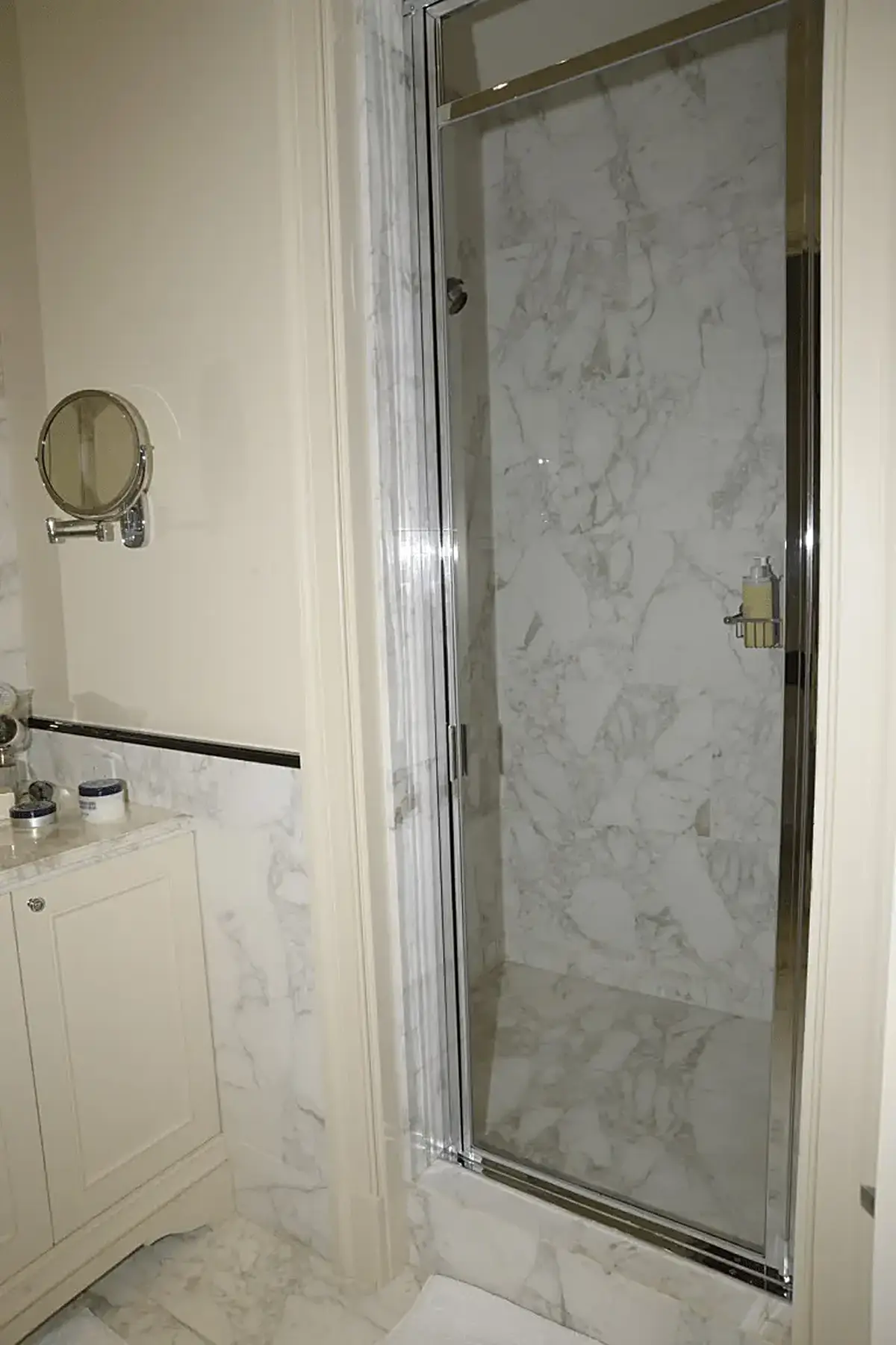 Bagno: EFTA00000605 - Luxurious bathroom featuring marble walls a glass shower door and a vanity 