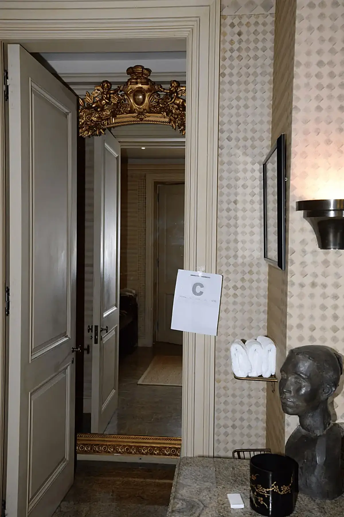 Bathroom: EFTA00000904 - Luxurious bathroom doorway features ornate gold mirror patterned wallpaper
