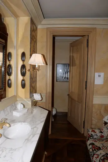 Badezimmer: EFTA00001023 - Luxurious bathroom features a marble countertop elegant wall sconces and a 