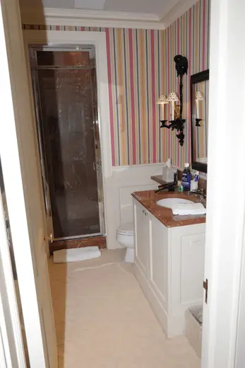 Badezimmer: EFTA00001111 - Bathroom with striped wallpaper a marble countertop a glass shower and whit