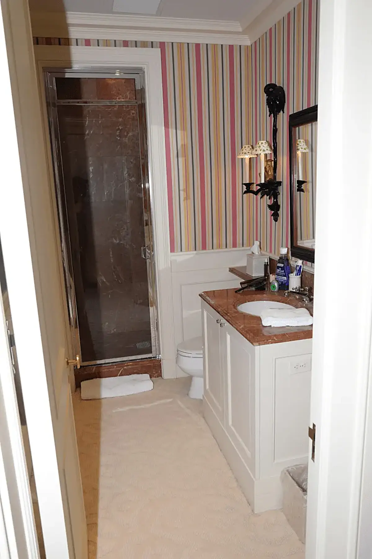 Salle de bains: EFTA00001111 - Bathroom with striped wallpaper a marble countertop a glass shower and whit