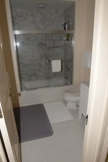 Badezimmer: EFTA00001163 - Small bathroom featuring a shower with marble tiles white fixtures and a gr