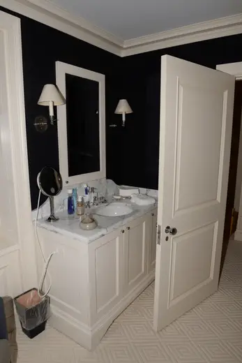 Badezimmer: EFTA00001179 - White bathroom vanity with marble countertop black walls and a partially op