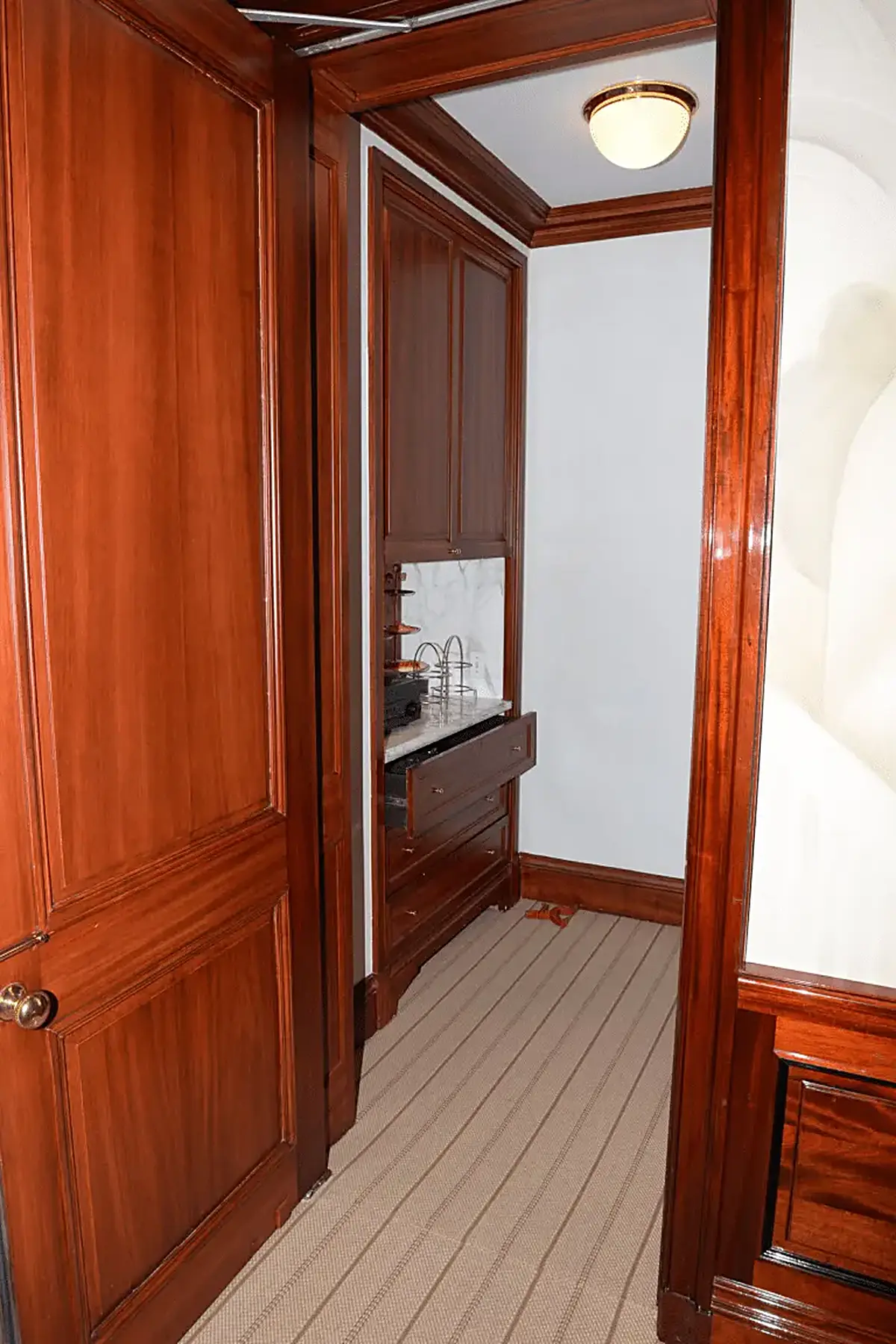 Badezimmer: EFTA00001452 - Wooden hallway leads to a small bathroom with a marble countertop drawers a