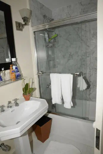 Badezimmer: EFTA00000296 - Bathroom with a white pedestal sink marble-tiled walls a glass shower enclo