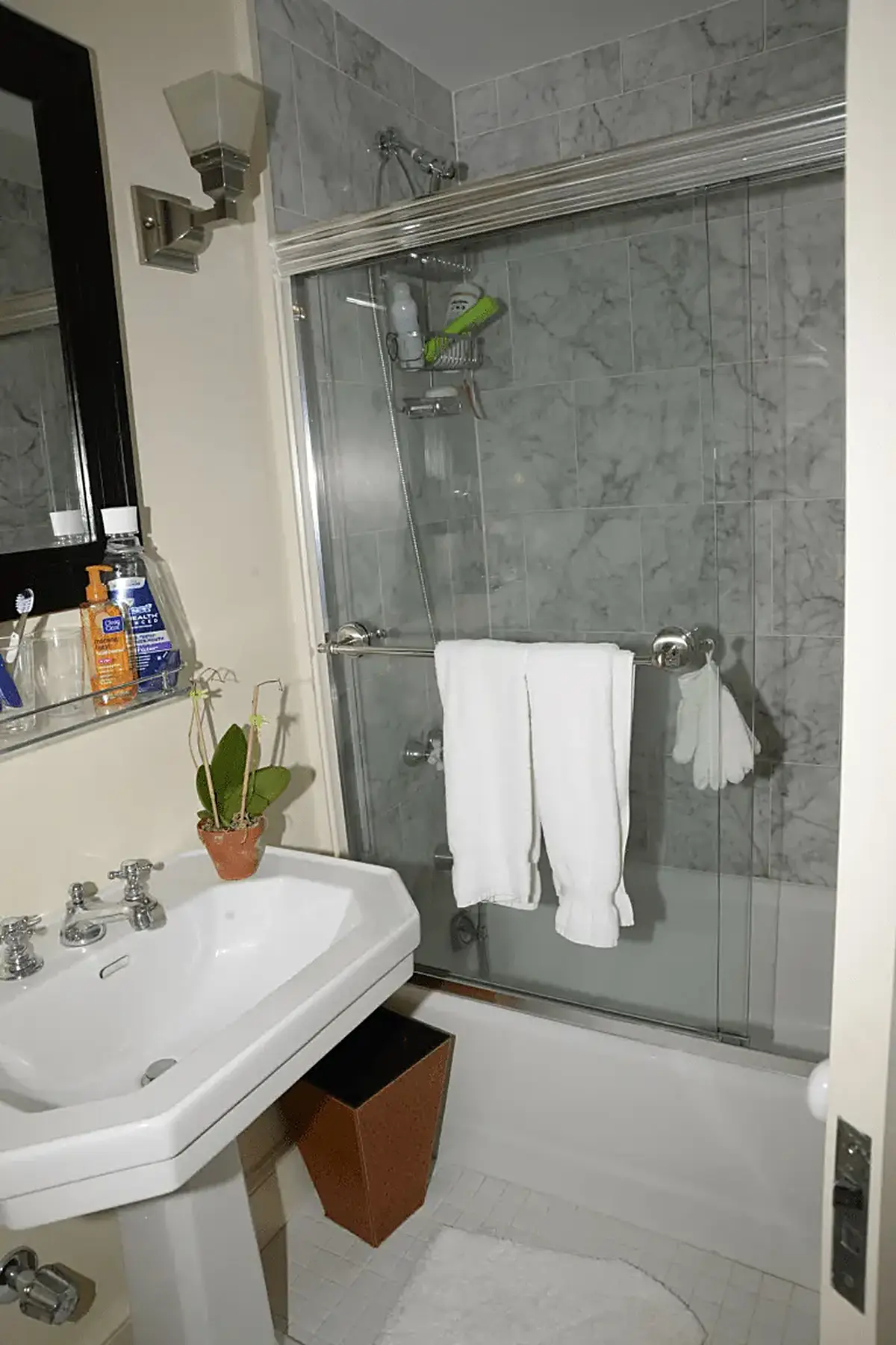 Ванная: EFTA00000296 - Bathroom with a white pedestal sink marble-tiled walls a glass shower enclo