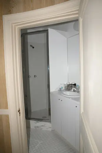 Baño: EFTA00000809 - White bathroom with glass shower door sink and marble floor tiles viewed th