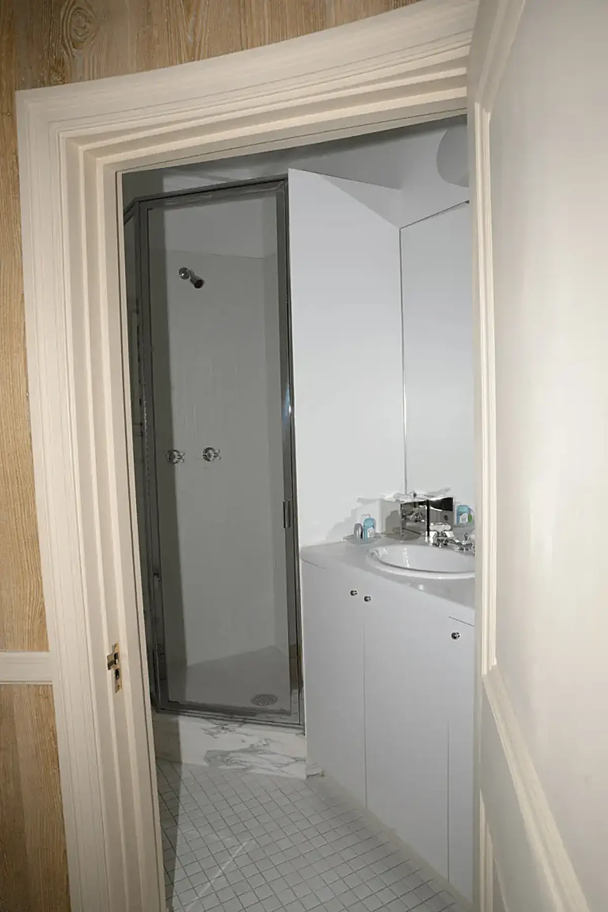 Ванная: EFTA00000809 - White bathroom with glass shower door sink and marble floor tiles viewed th