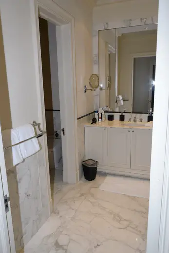 Badezimmer: EFTA00001116 - Modern bathroom featuring marble flooring white cabinets a large mirror and