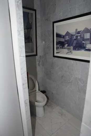 Badezimmer: EFTA00002891-Pool-House - Small bathroom with gray marble walls a white toilet and framed 