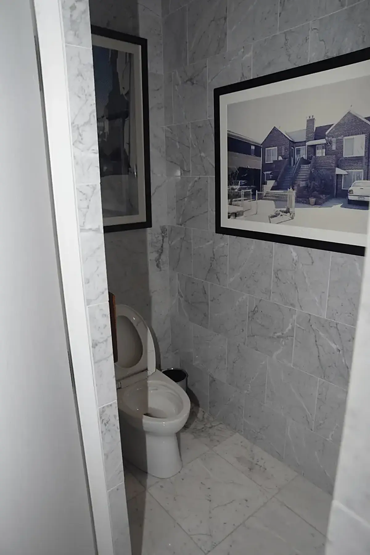 Baño: EFTA00002891-Pool-House - Small bathroom with gray marble walls a white toilet and framed
