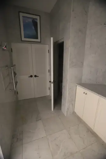 Badezimmer: USVI IMG 5424 - Modern bathroom with marble floors and walls white cabinets a framed pictu