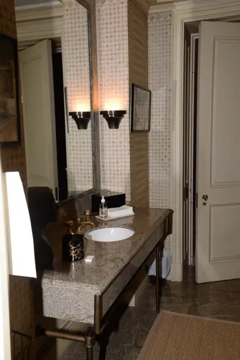 Badezimmer: EFTA00000908 - Bathroom with a granite countertop white sink gold fixtures patterned wallp