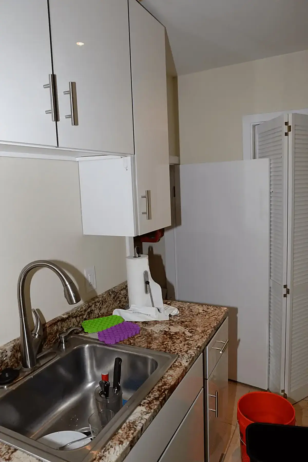 Badezimmer: EFTA00002187 - Kitchen sink with dishes and cleaning supplies set against granite countert