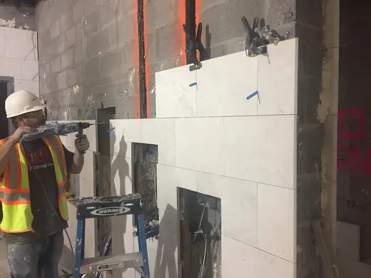Badezimmer: Continued installation of marble finishes along the west wall of the women’s bathroom in t