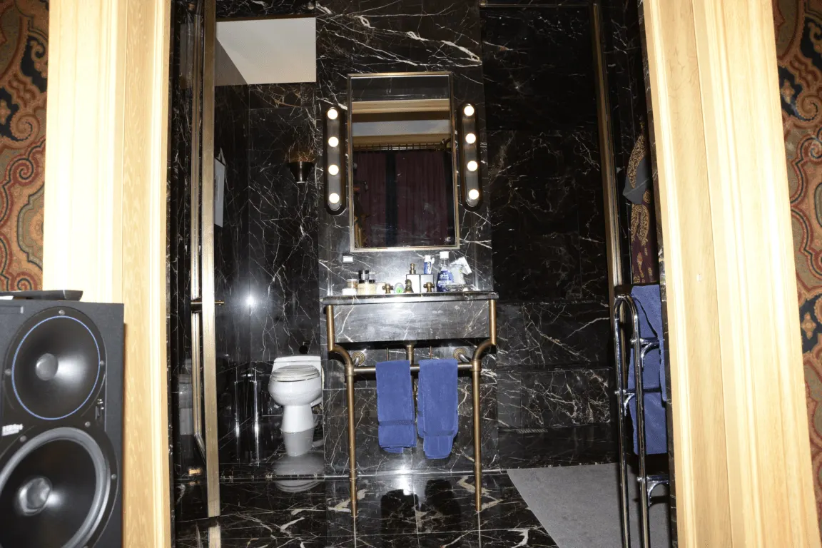 Baño: EFTA00000173 - Luxurious bathroom with black marble walls a gold-framed mirror with lights