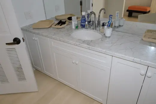 Ванная: EFTA00001599 - White marble bathroom counter with sink faucet and toiletries A white door 
