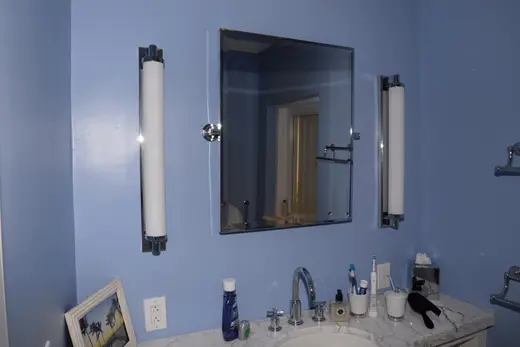 Ванная: EFTA00001792 - Bathroom with blue walls a marble countertop and a mirror flanked by two wh