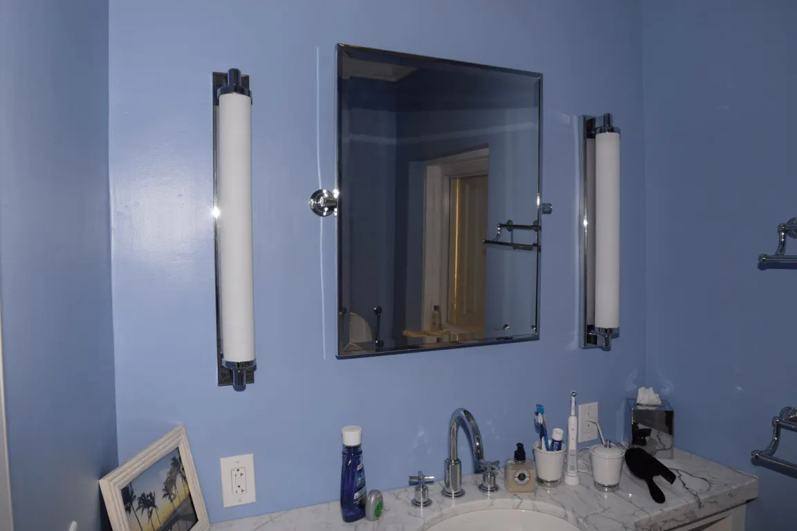 Salle de bains: EFTA00001792 - Bathroom with blue walls a marble countertop and a mirror flanked by two wh