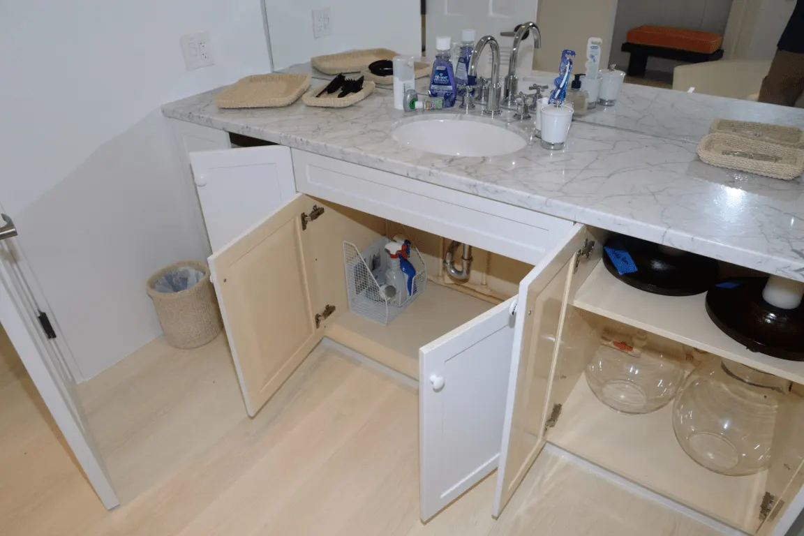 Bagno: EFTA00002046 - Bathroom sink with a marble countertop and open cabinet revealing cleaning