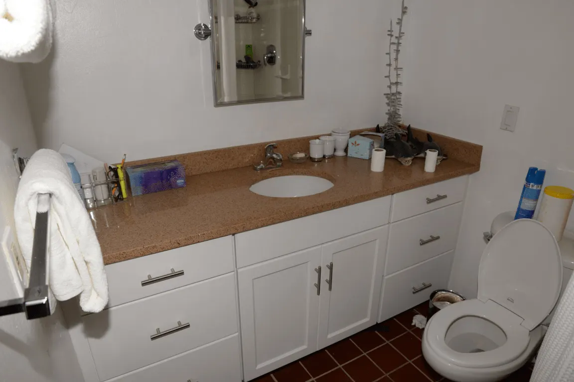 Badezimmer: EFTA00001701 - White bathroom with tan countertop sink mirror and toilet A towel hangs on 