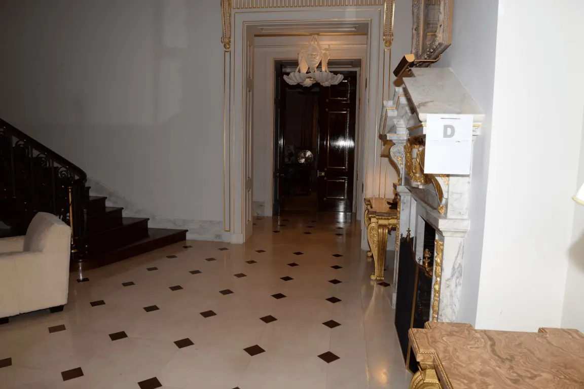 Pavimento: EFTA00001493 - Grand hallway features a marble floor ornate fireplace and a staircase lead