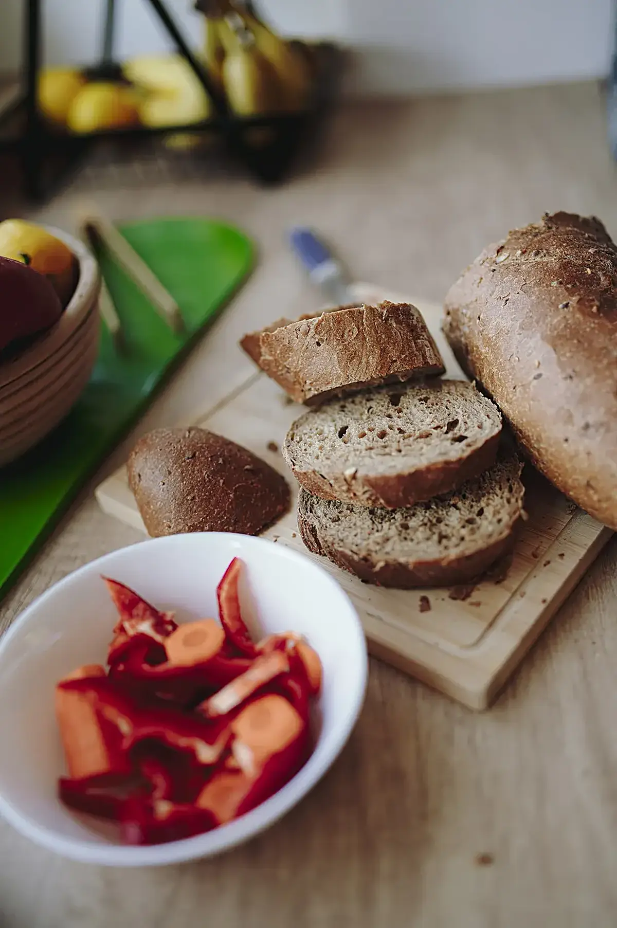 Küche: Freshly sliced bread alongside colorful vegetable slices on a wooden countertop in a kitch