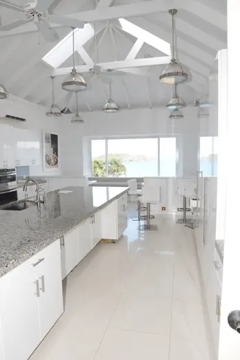Kitchen: EFTA00001524 - Bright white kitchen with granite countertops skylights and ocean view thro