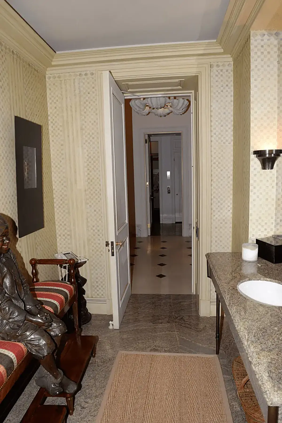Cocina: EFTA00000937 - Hallway with patterned wallpaper a marble countertop and a bronze statue le