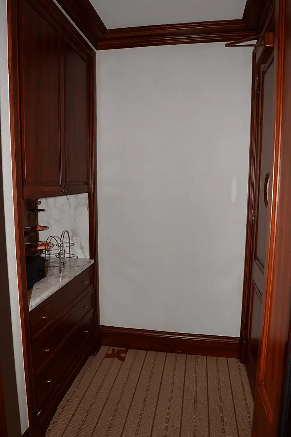 Cuisine: EFTA00000952 - Narrow hallway with dark wood cabinetry a marble countertop and striped car