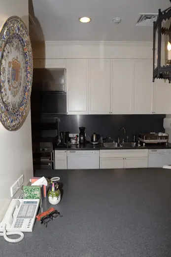 Kitchen: EFTA00000958 - Modern kitchen with white cabinets a dark countertop and a decorative plate