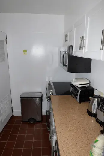 Kitchen: EFTA00001695 - Compact kitchen with white cabinets a speckled countertop and a stainless s