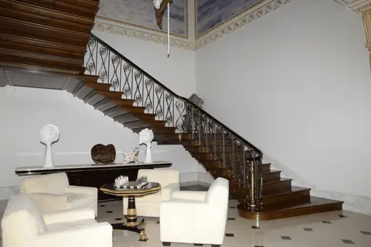 Scala: EFTA00000053 - Grand wooden staircase with intricate iron railings ascends flanked by whit