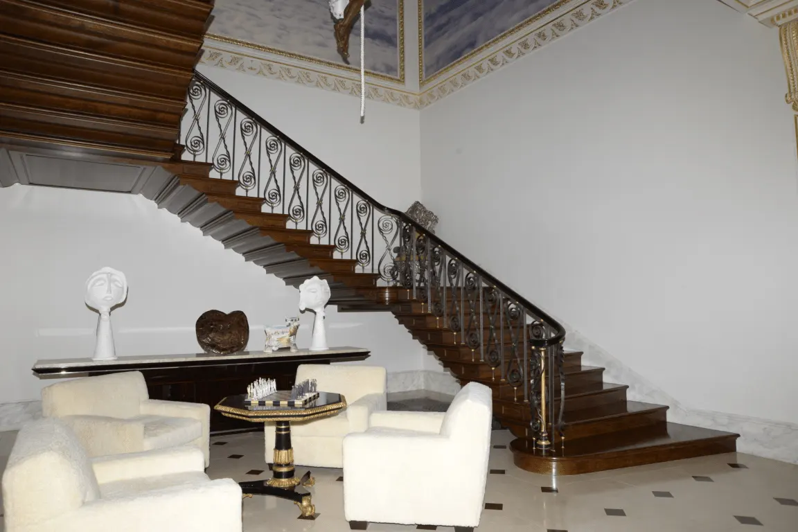 Лестница: EFTA00000053 - Grand wooden staircase with intricate iron railings ascends flanked by whit